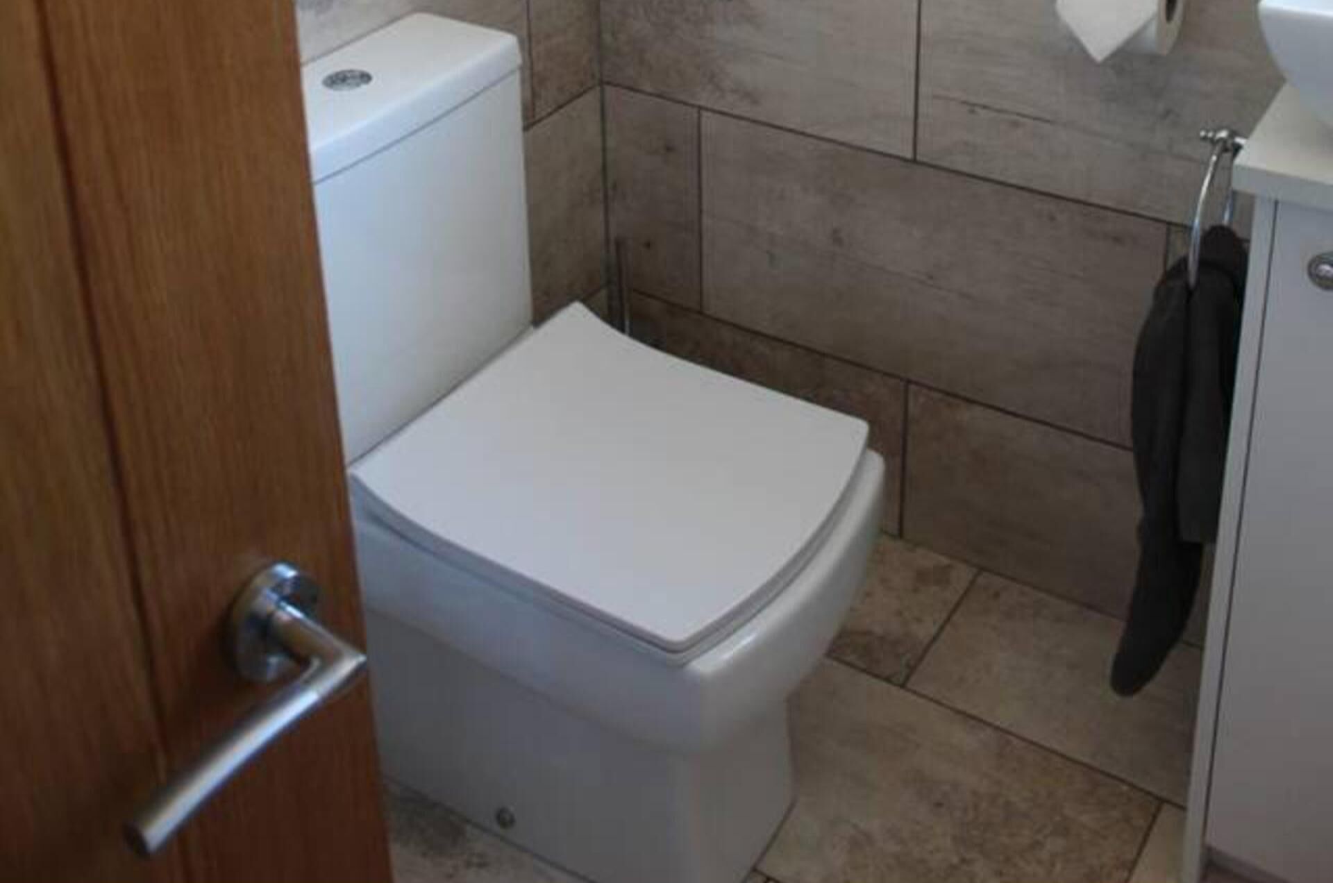 A small, compact bathroom with a toilet, a sink, and a towel rack.