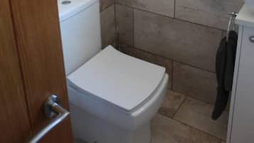 A small, compact bathroom with a toilet, a sink, and a towel rack.
