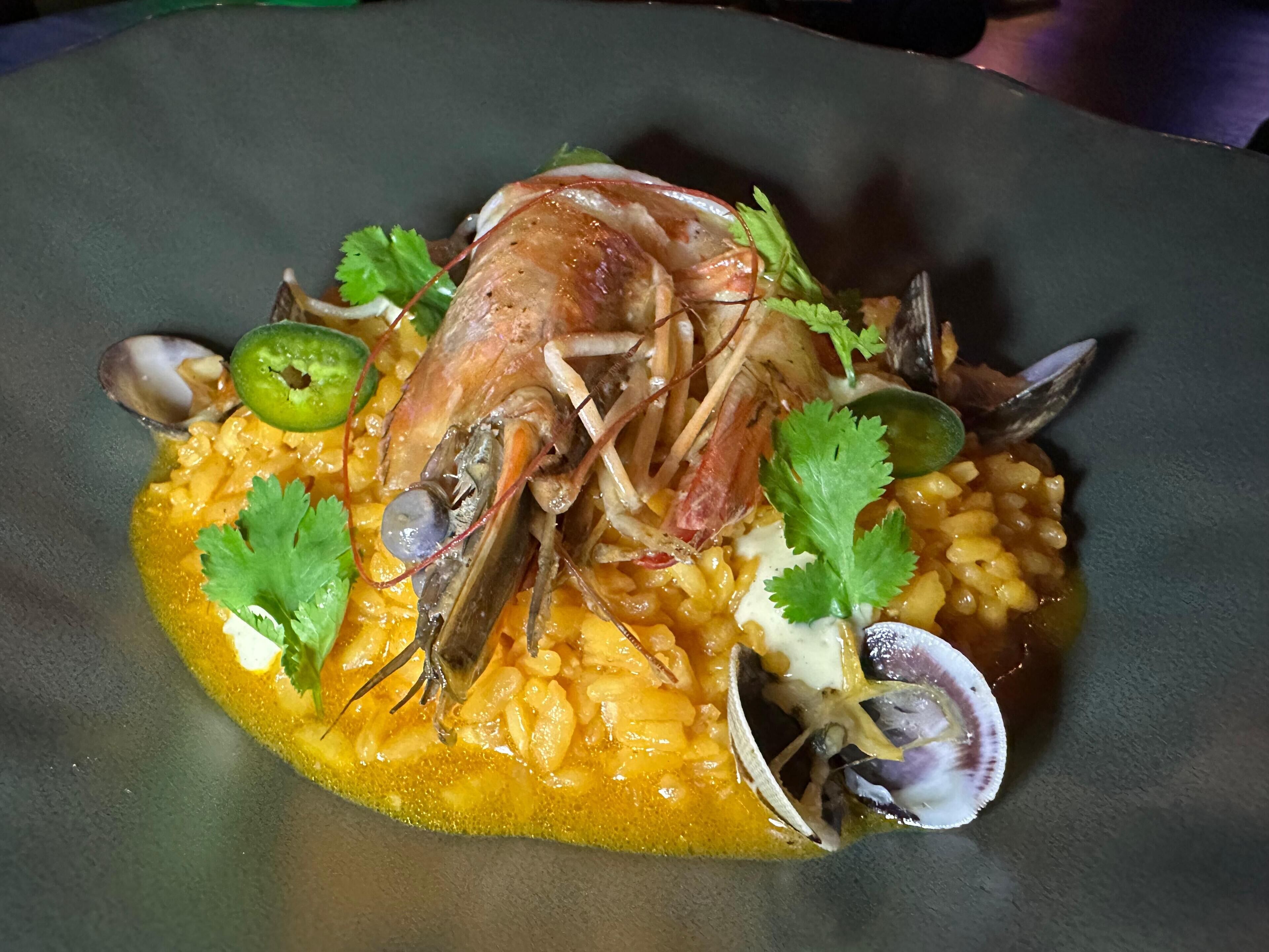 Un plat de fruits de mer composé de moules, de palourdes et de crevettes, servi sur un lit de riz.