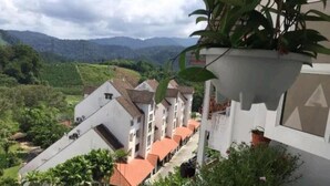 A row of white buildings with red roofs, surrounded by greenery and hills in the background. - Cosy Selesa Hillhomes and Golf Resort (Bukit Tinggi)