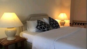 A neatly made bed with white bedding and black geometric pillows, flanked by two bedside lamps on wooden nightstands. - Cosy Selesa Hillhomes and Golf Resort (Bukit Tinggi)