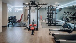 Une salle de sport équipée de divers appareils d’exercice, notamment un support à squats, des bancs et des appareils de cardio.
