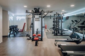 Une salle de sport équipée de divers appareils d’exercice, notamment un support à squats, des bancs et des appareils de cardio.