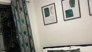 A bedroom with a bed, a window with curtains, and two framed pictures on the wall. - Two bedroom Central Apartment - ground floor (Exeter)