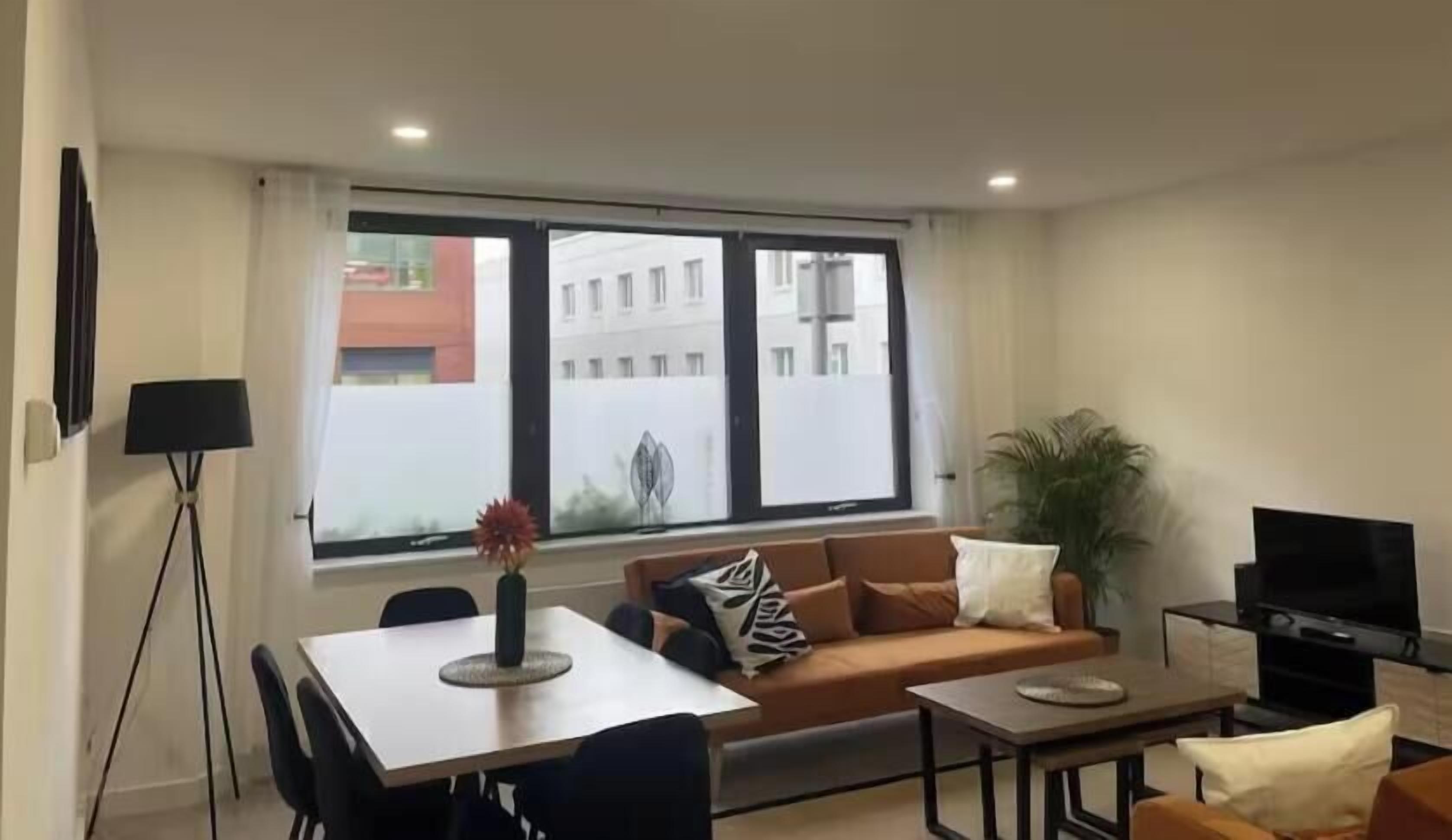 A modern living room with a sofa, a dining table, and a television.