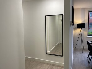 Une chambre moderne avec un grand miroir au mur, un lampadaire et un coin repas avec des chaises.