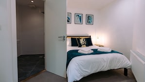 Une chambre à coucher comprenant un lit, un espace douche et une porte donnant sur une autre pièce.