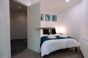 Une chambre à coucher avec un lit, une table de chevet et une lampe fixée au mur.