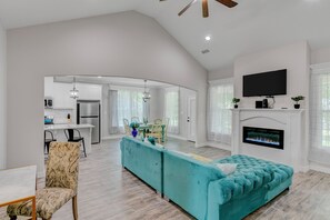 Un salón espacioso con un sofá color turquesa, una chimenea y un televisor colocado encima.