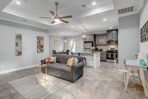 A modern kitchen with a central island, grey cabinetry, and stainless steel appliances.