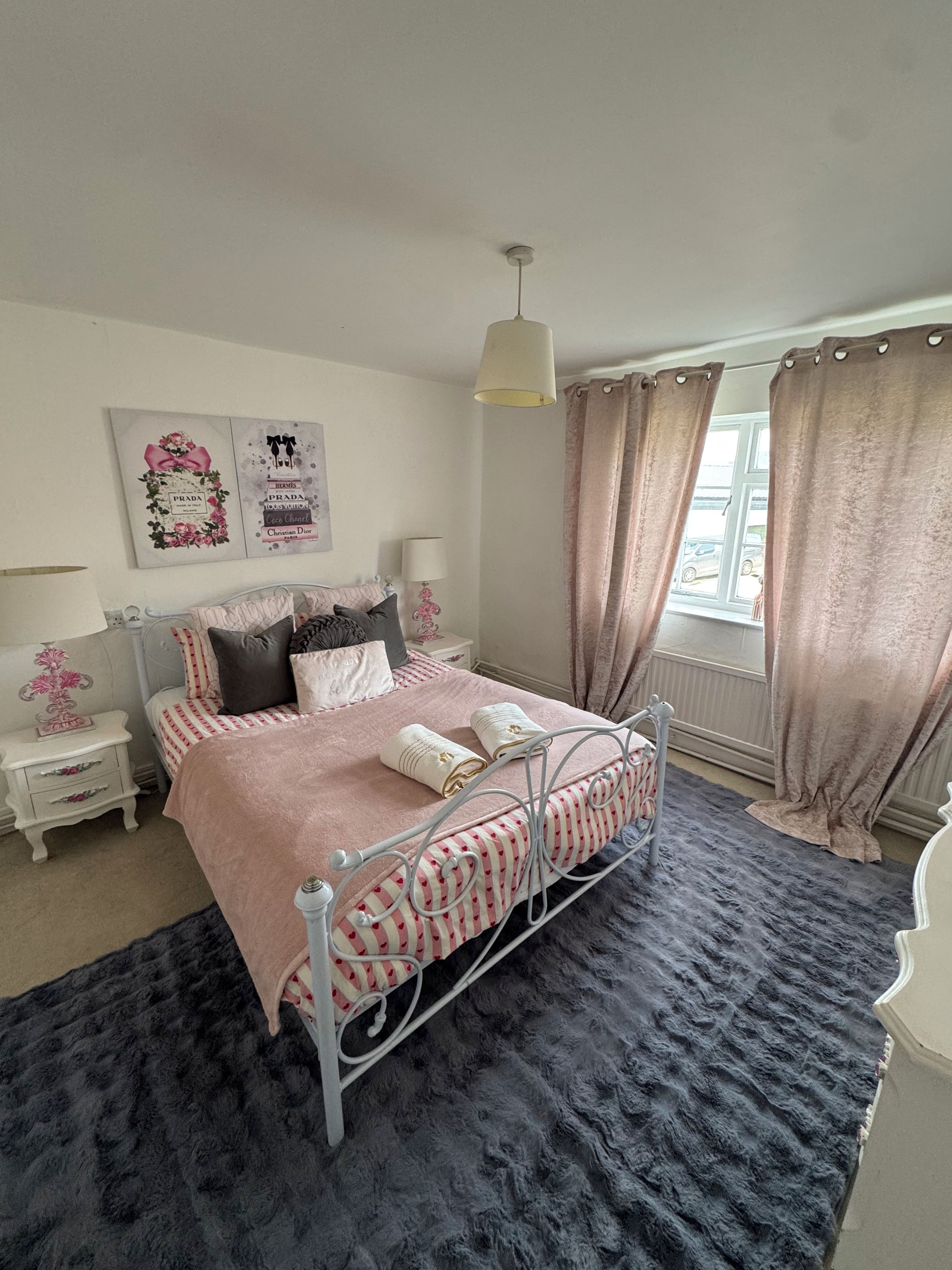 Une chambre à coucher avec un lit, des tables de chevet, une lampe et des rideaux.