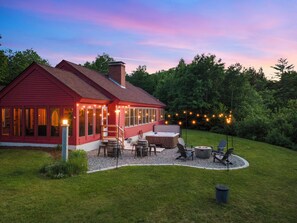 A red house with a deck, outdoor seating, and string lights.
