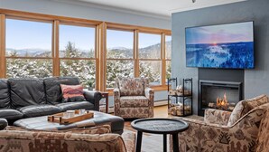 Una sala de estar moderna con chimenea, ventanas amplias y un televisor.