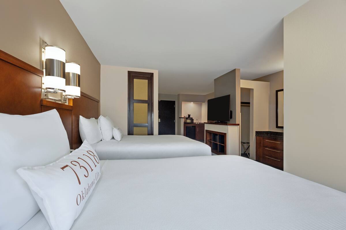 Habitación de hotel con dos camas, televisión, minibar y baño.