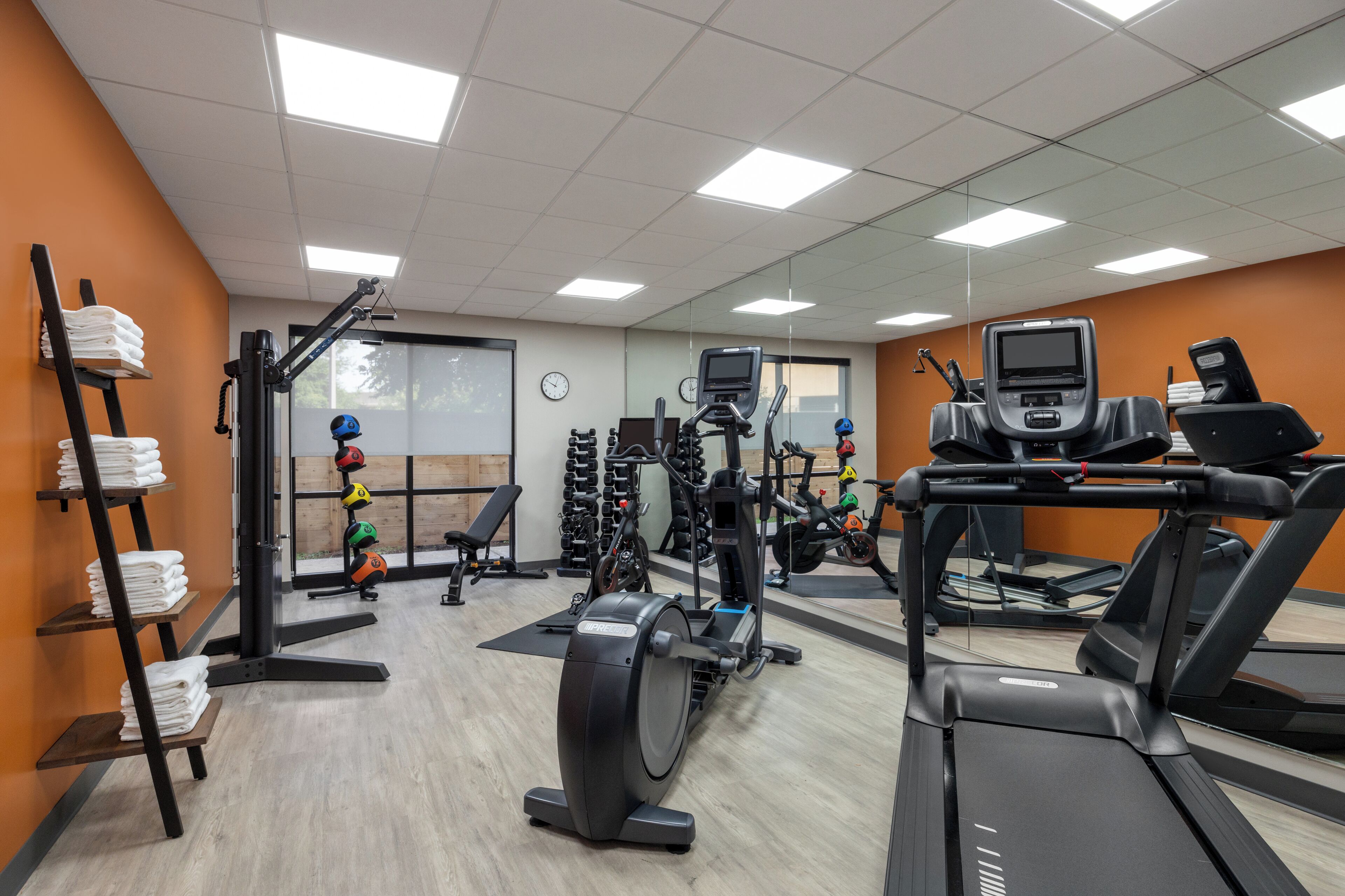 A gym with treadmills, weight machines, and a wall-mounted TV.