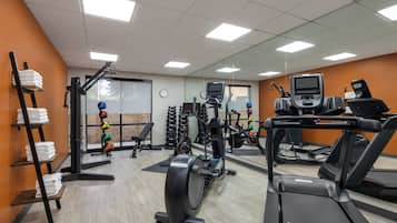 A gym with treadmills, weight machines, and a wall-mounted TV.