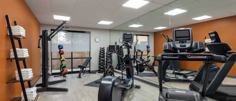 A gym with treadmills, weight machines, and a wall-mounted TV.