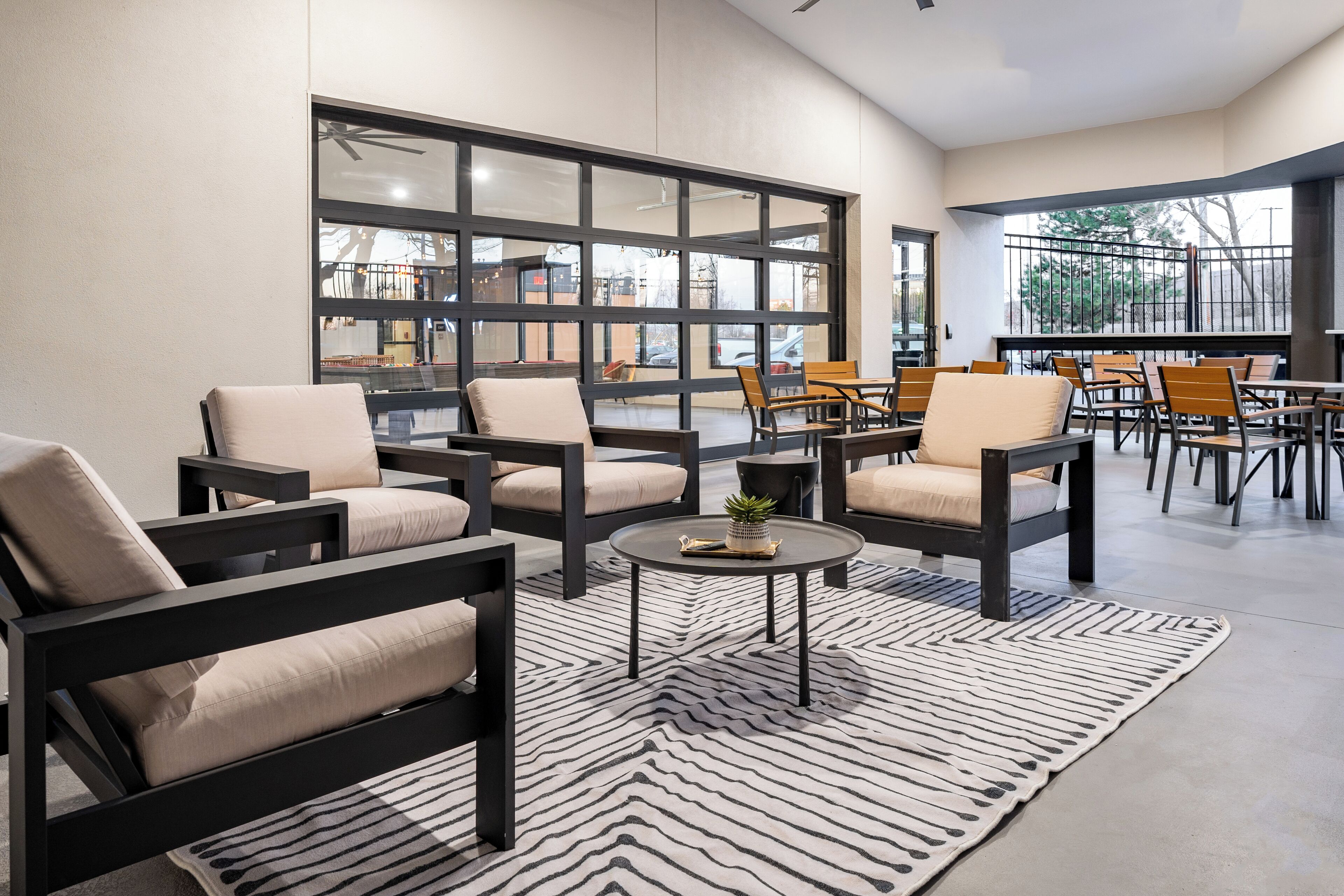 A modern lounge area with sofas and tables, large windows, and a view of the outside.