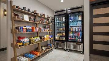 Un área bien surtida para aperitivos y bebidas, con estantes llenos de bocadillos y dos refrigeradores para bebidas.