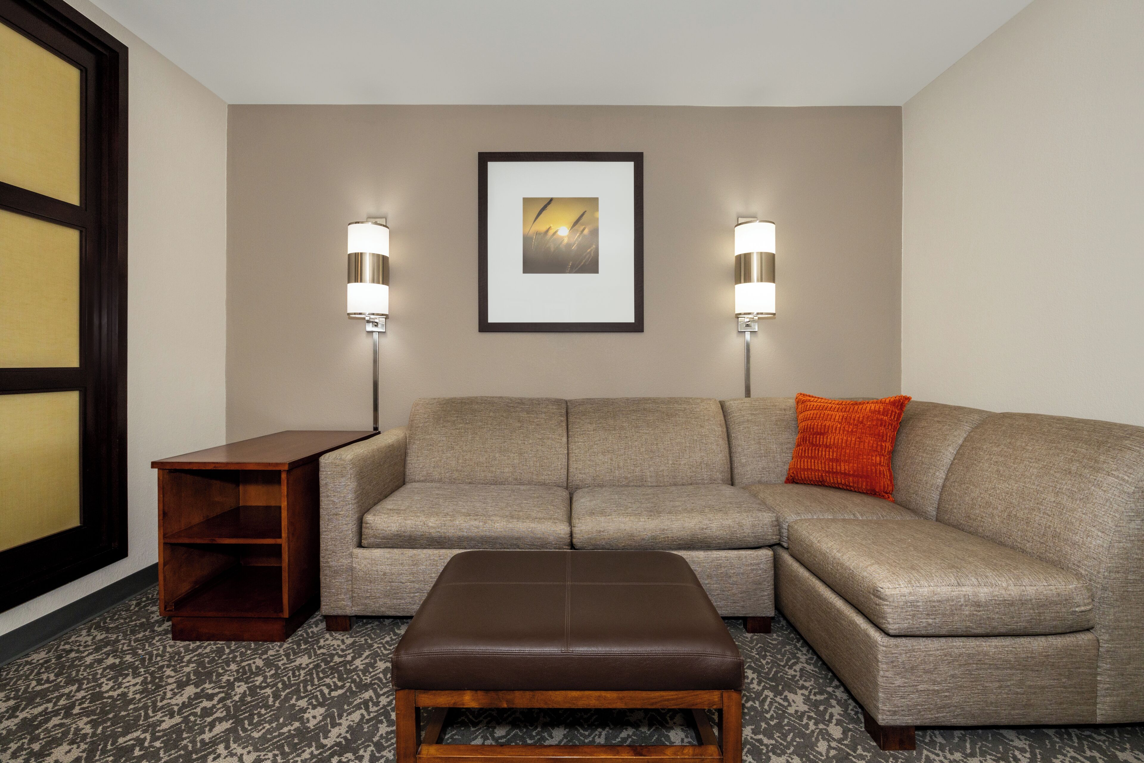 A living room with a sectional sofa, a wooden side table, and a framed picture on the wall.