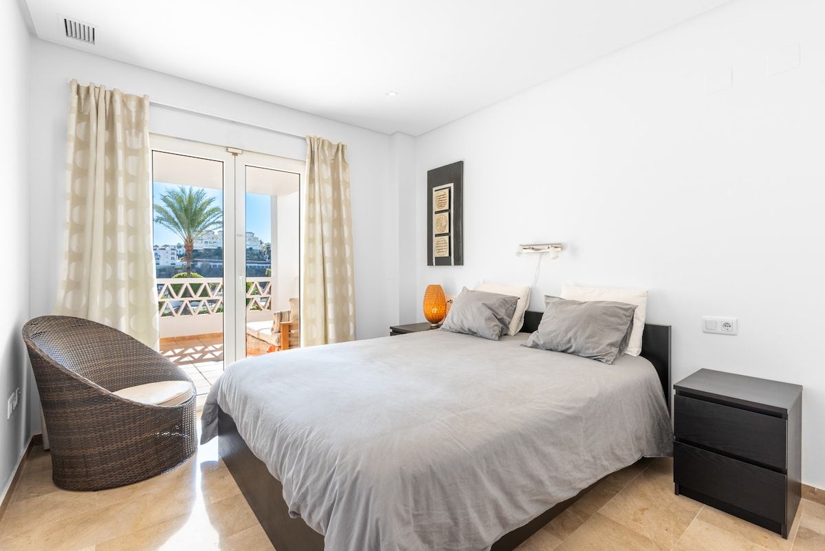Una camera da letto con un letto, un comodino, una sedia e vista all'esterno.