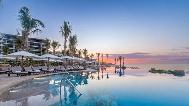 A resort pool with lounge chairs, umbrellas, and palm trees. -  2 Bedroom Suite at Villa la Valencia Beach Resort  (San José del Cabo)