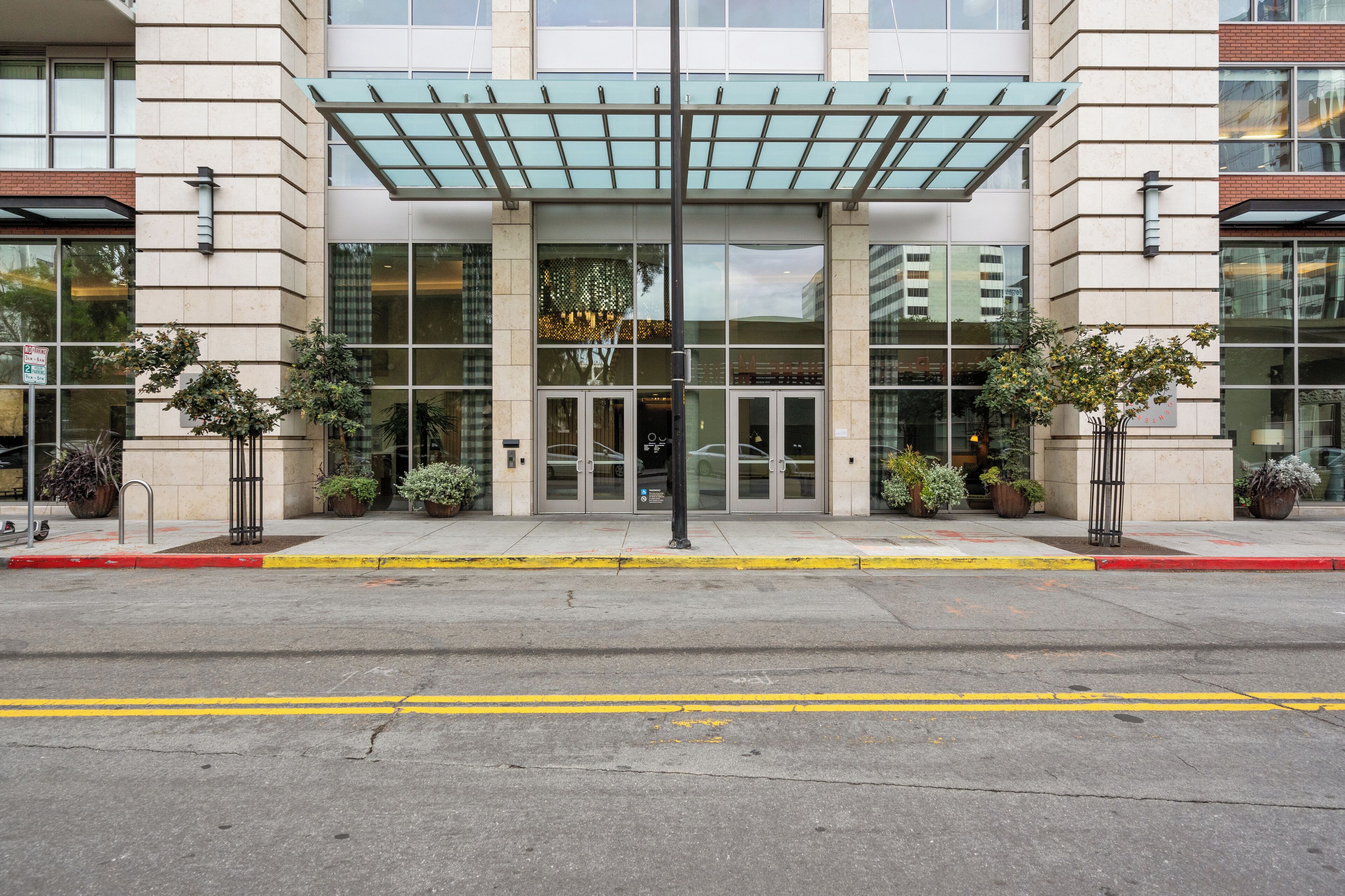 A modern building with a glass entrance, potted plants, and a clear sky.