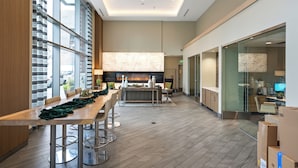 Un hall d’hôtel moderne avec un long comptoir d’accueil, un espace salon et une cheminée.