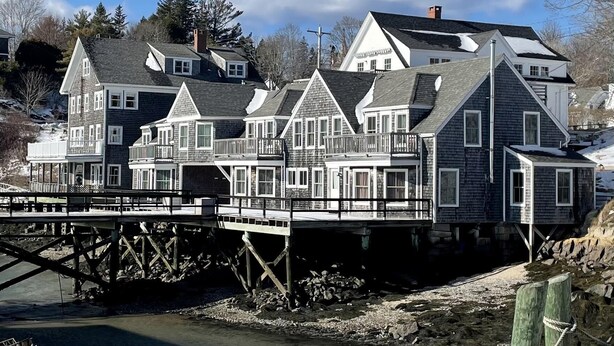 Une propriété située au bord de l’eau, comprenant plusieurs maisons, un quai et une côte rocheuse.