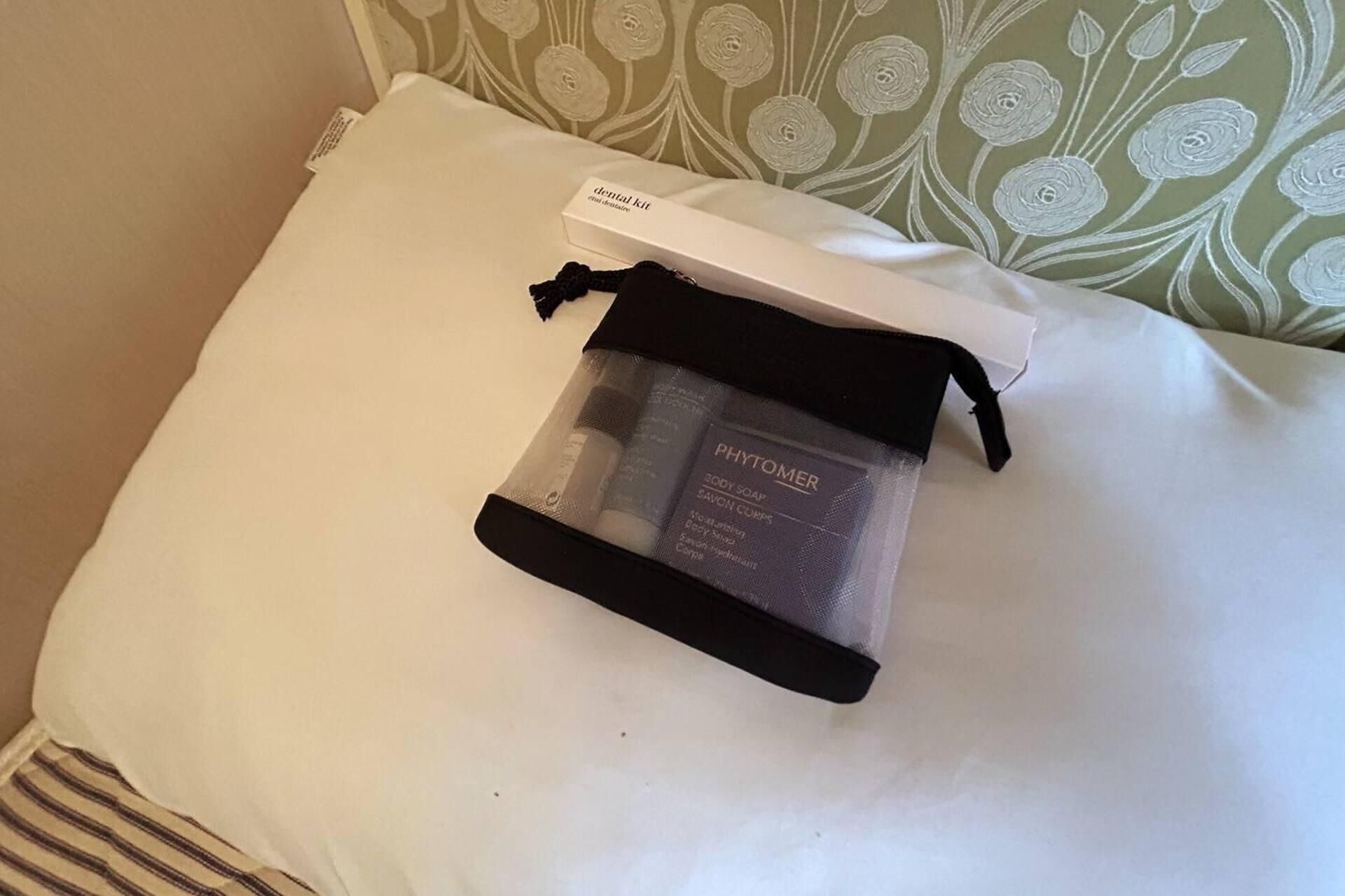 A white pillow with a floral pattern and a small white box labeled "Dental Kit" on it.