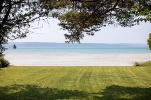 Enjoy a serene beachfront setting with a clear view of the calm sea and a small boat on the water.