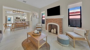 Un salon moderne avec une cheminée, un téléviseur et un coin repas.