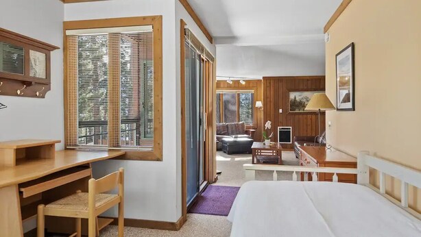 A bedroom with a bed, a desk, and a chair. There is a window with blinds, a door leading to another room, and a lamp on the desk. - Mammoth Getaway, Short walk to the Village and steps to Canyon Lodge shuttle. (Mammoth Lakes)