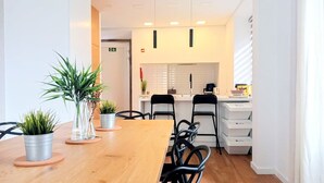 A modern dining area with a wooden table, black chairs, and potted plants. - SurfSoul B&B (Peniche)