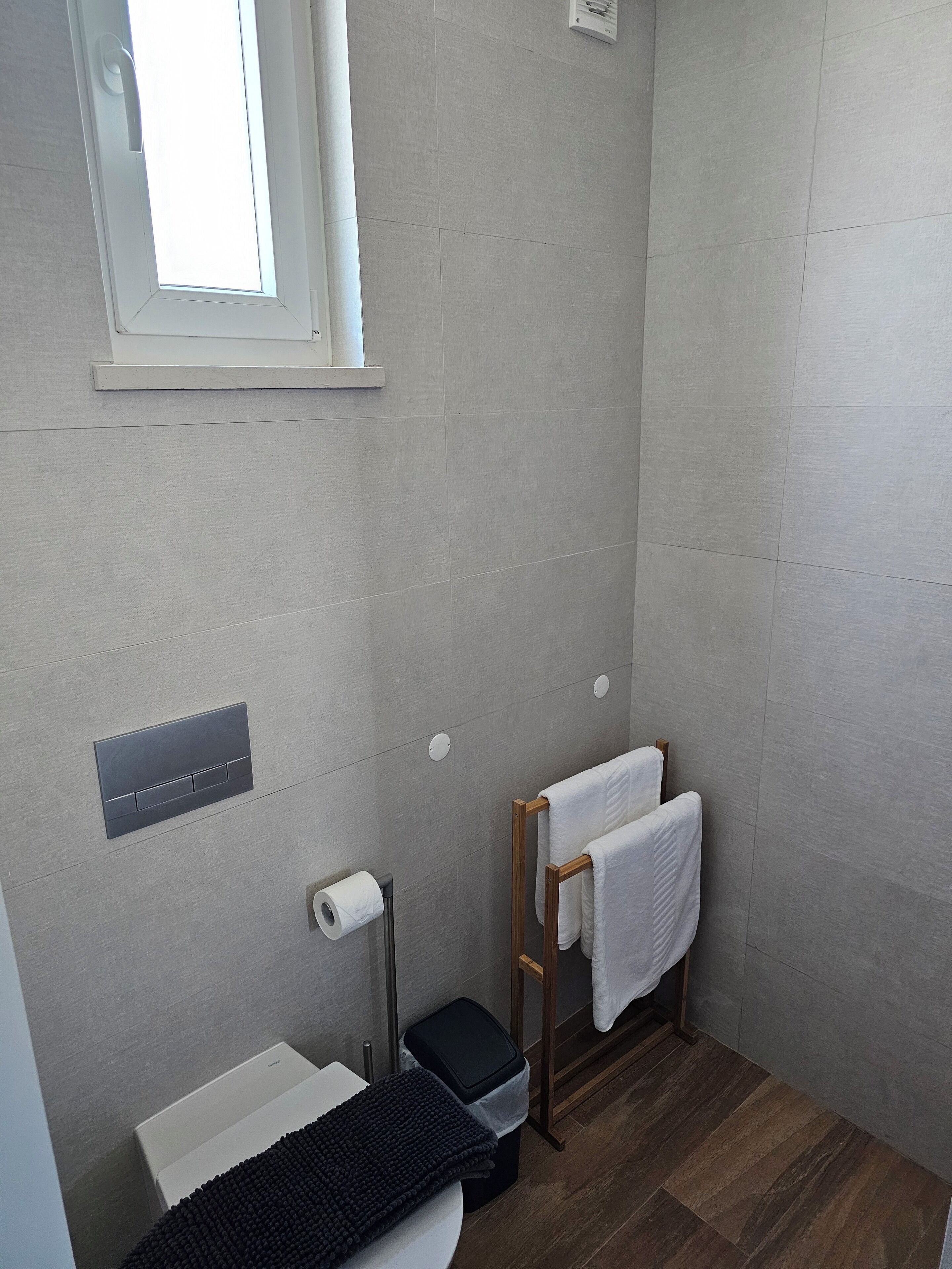 Une petite salle de bain comprenant des toilettes, un lavabo, un porte-serviettes et une fenêtre.