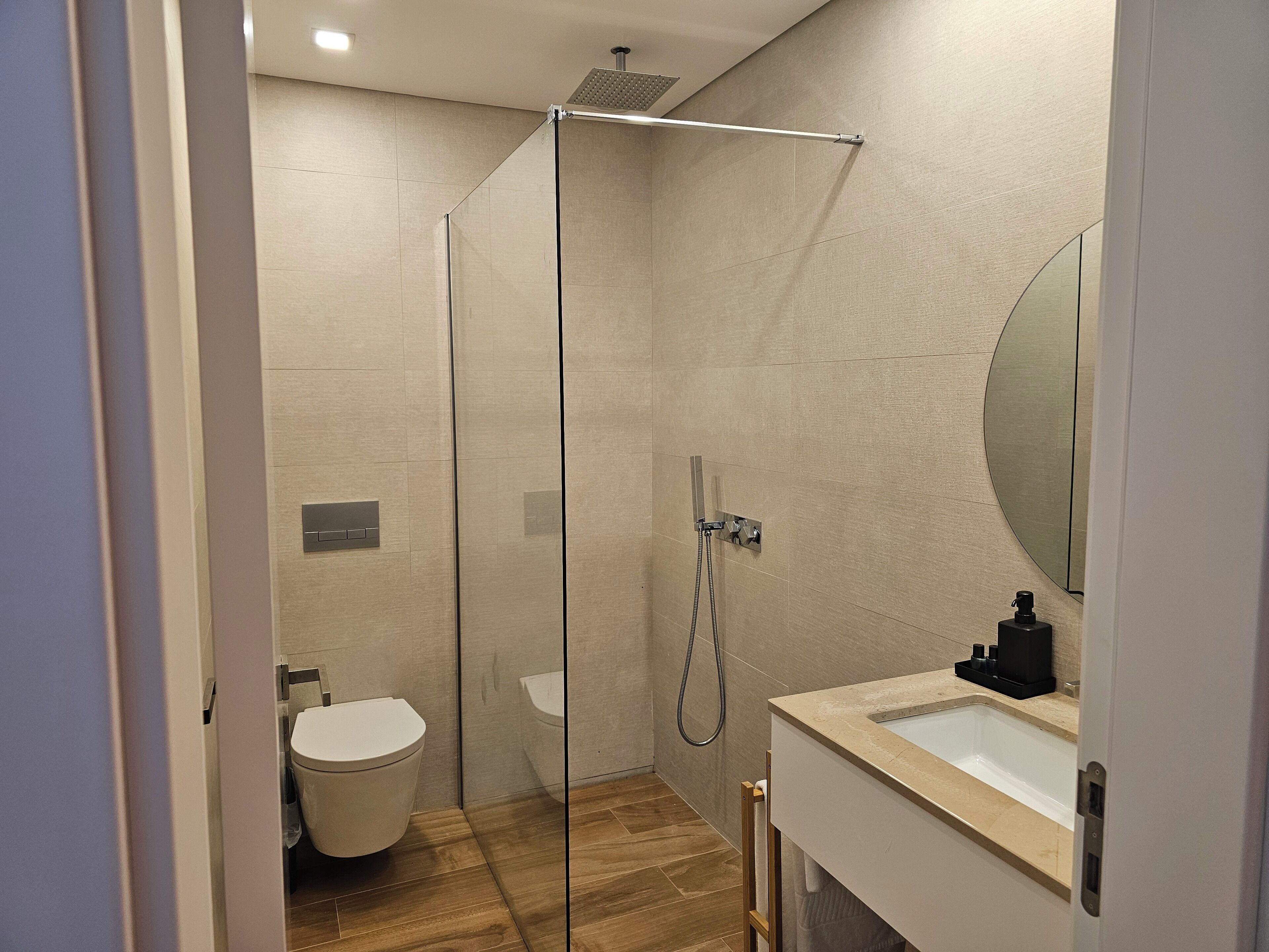 Ein modernes Badezimmer mit einer Duschkabine, einer Toilette und einem Waschbecken mit Spiegel.
