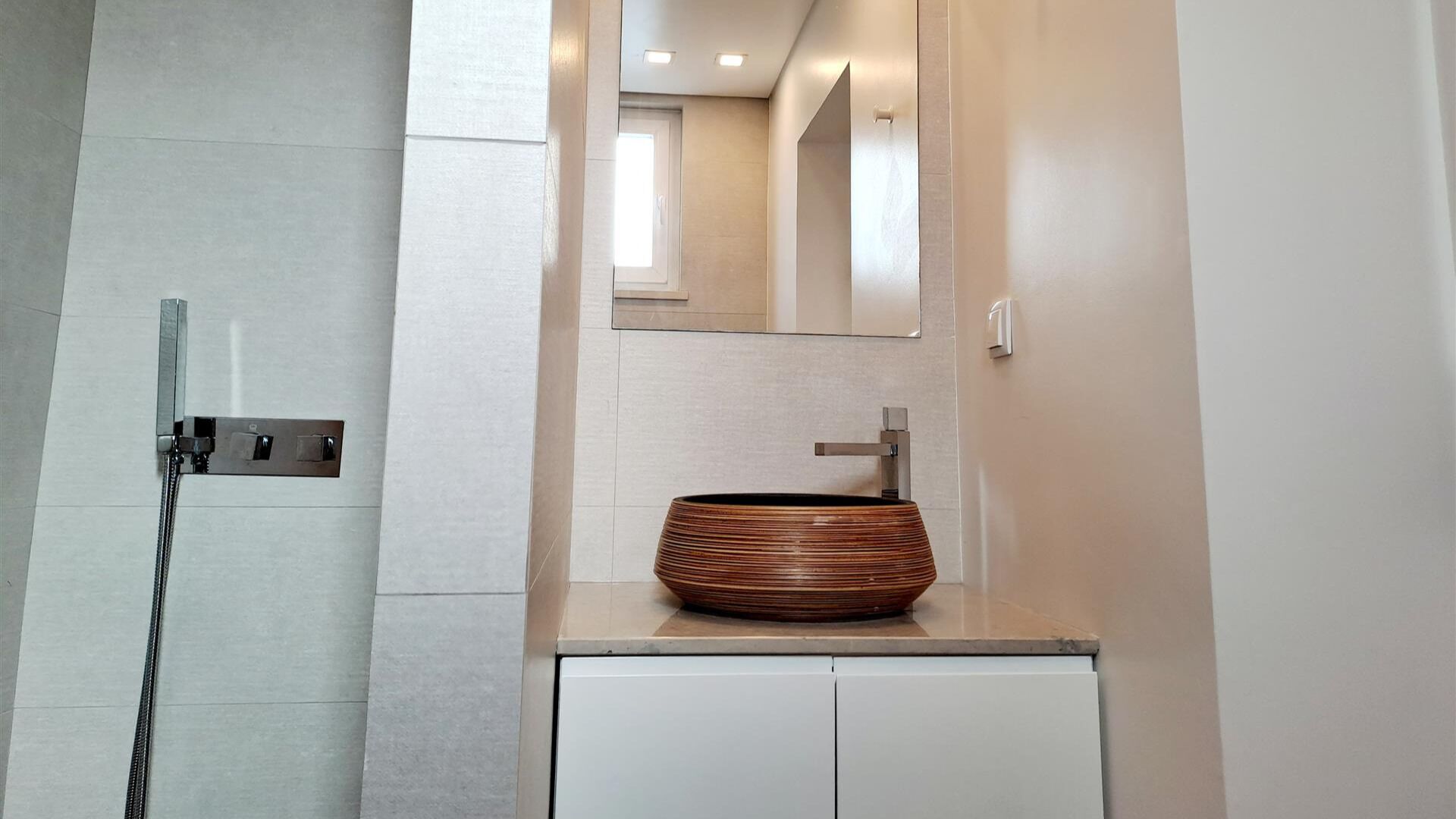 Une salle de bain moderne avec un grand miroir, un lavabo sur colonne et un espace douche.
