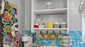 Una cocina con lavavajillas, un estante blanco con adornos y un colorido cuadro de peces.
