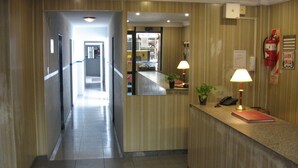 A hotel reception area with a reception desk, two lamps, a fire extinguisher, and a sign on the wall. - Hotel Wilton BA (Buenos Aires)