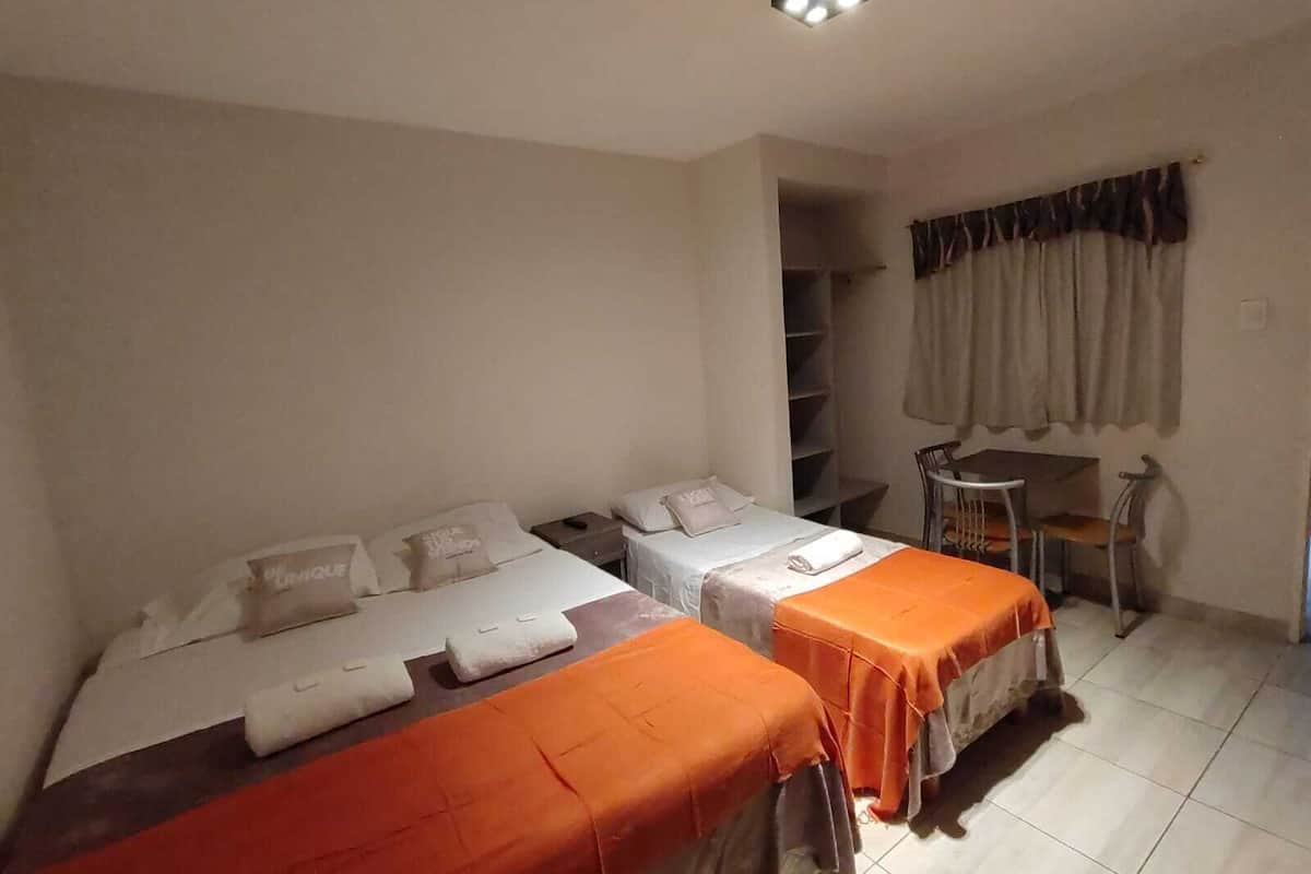 A room with two beds, a desk, and a chair.
