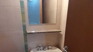 A bathroom with a pedestal sink, a mirror above it, and a door leading to another room. - Hotel Wilton BA (Buenos Aires)