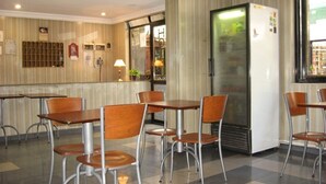 A hotel lobby with a check-in counter, seating area with tables and chairs, a refrigerator, and a window with a view of the outside. - Hotel Wilton BA (Buenos Aires)