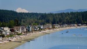 Un pueblo costero con casas a lo largo de la playa, barcos en el agua y una montaña al fondo.