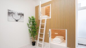 A bunk bed room with a ladder, a potted plant, and a framed picture on the wall. - Robin Wood Apartment (Vienna)