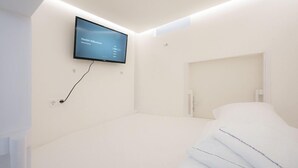 A modern hotel room with a large flat-screen TV mounted on the wall, a neatly made bed, and a minimalist design. - Robin Wood Apartment (Vienna)