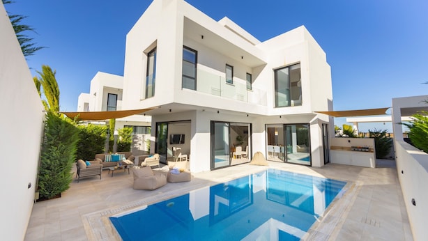 A modern two-story house with a swimming pool, outdoor seating, and a large glass door entrance. - Protaras Periyiali Seaside Villa 33 (Protaras)
