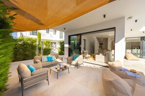 An outdoor patio with sofas, a coffee table, and a large umbrella.