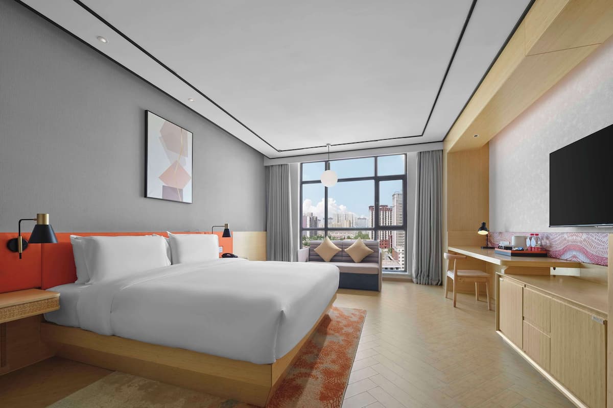Ein modernes Hotelzimmer mit einem großen Bett, einem Schreibtisch und einem Fernseher.