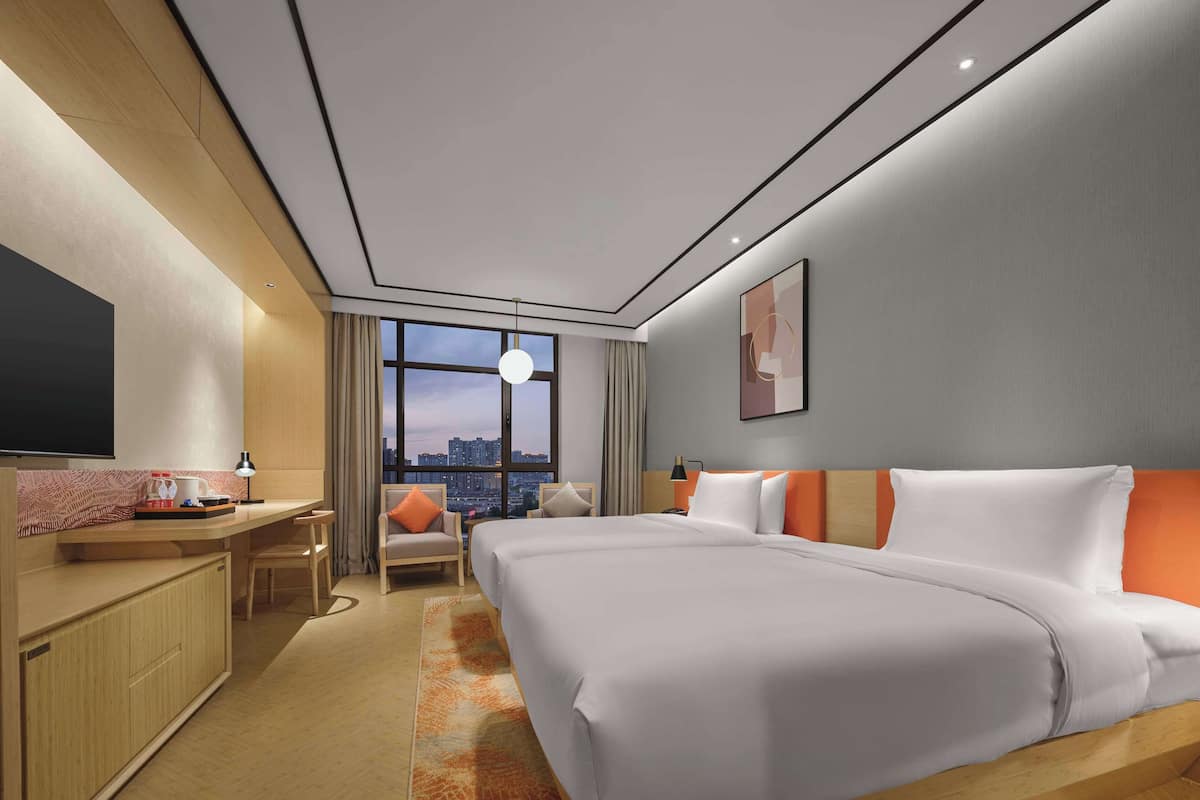 Ein modernes Hotelzimmer mit einem großen Bett, einem Schreibtisch und Blick auf die Stadt.