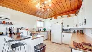 Una cucina moderna con soffitto in legno, mobili bianchi ed elettrodomestici in acciaio inossidabile.